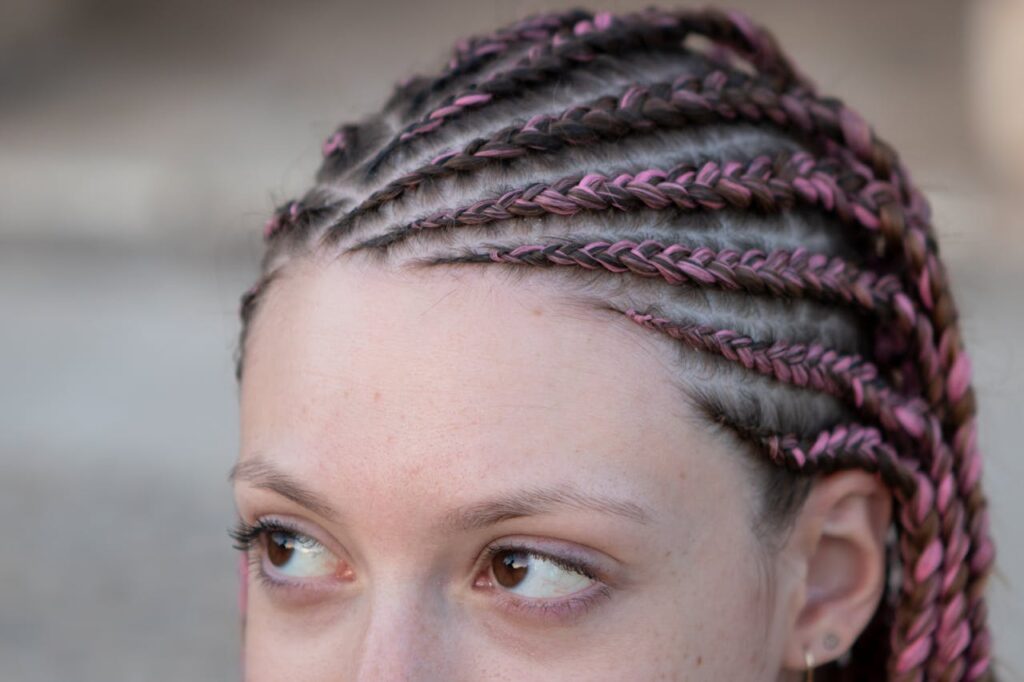 Crafting Captivating Headlines: Your awesome post title goes here Detailed view of a woman featuring intricate pink and brown braided hairstyle, highlighting modern fashion.