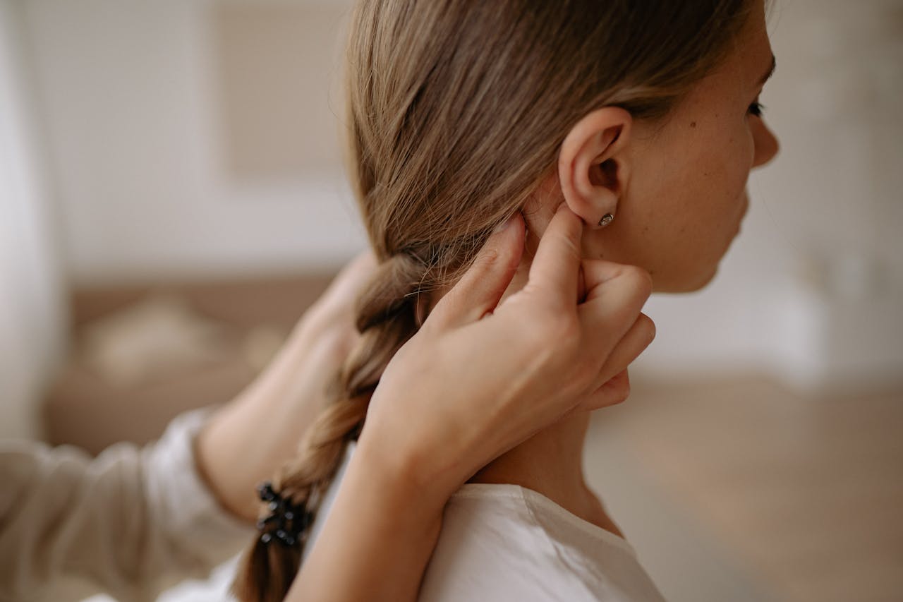 A female hair styled into a neat braid by another person indoors.
